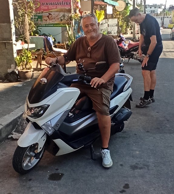 Viajero sobre una moto de alquiler en Chiang Rai, con casco puesto y listo para recorrer los alrededores de la ciudad. Alquilar una moto es una de las mejores formas de desplazarse de forma independiente y llegar al Templo Blanco de Chiang Rai (Wat Rong Khun) y otros templos de la zona, con precios que rondan los 200-300 baht al día.